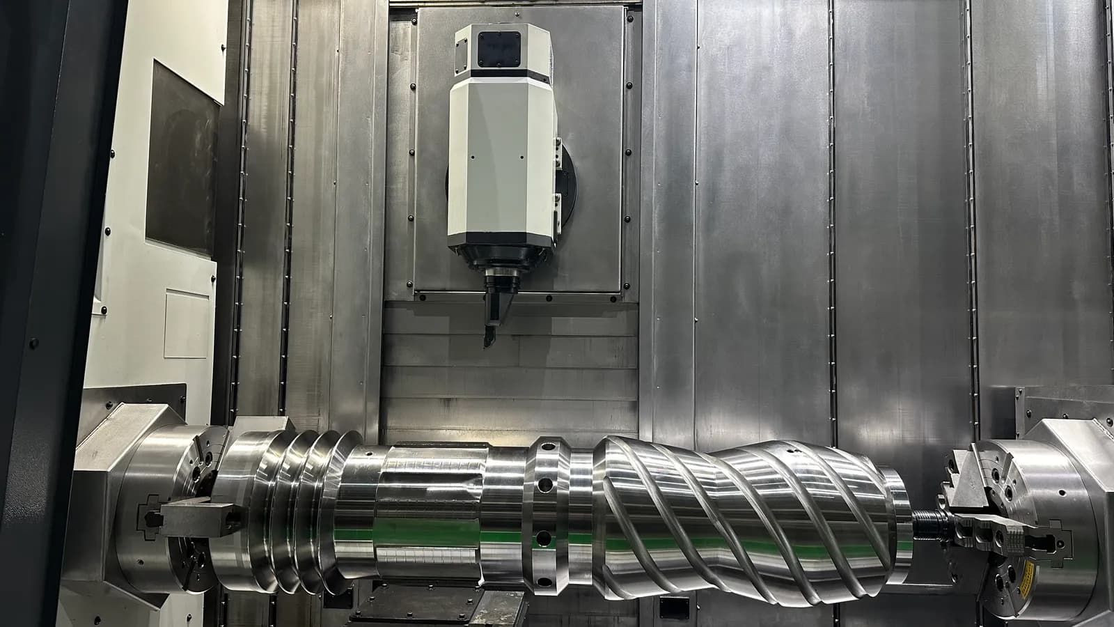 CNC machine cutting a precision shaft under coolant